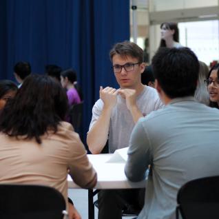 students and professional sitting at a table networking