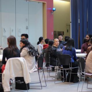 students and professional sitting at a table networking
