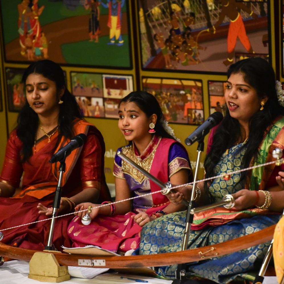Three singers in front of mics in very colourful traditional sari's
