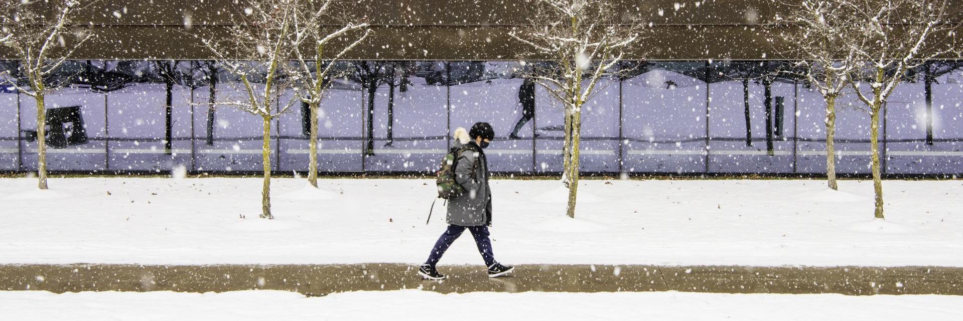 student walking on campus during winter storm