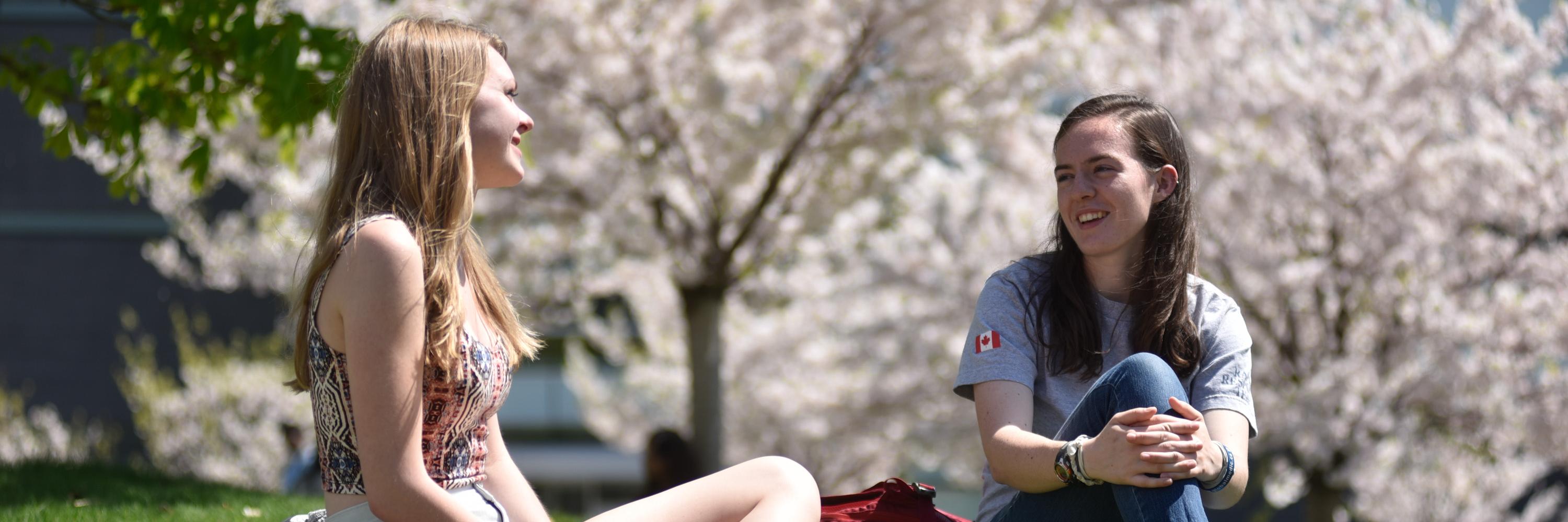 Two students in front of the cherry blossom trees in spring