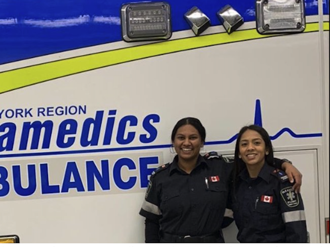 Two paramedics students sstanding in front of an Ambulance