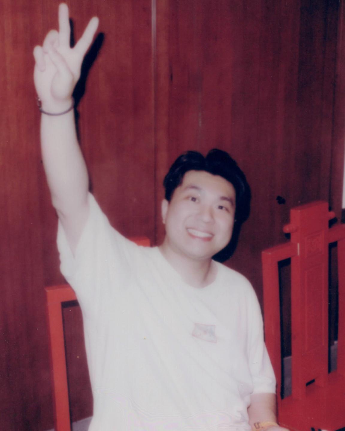 A film style photo of Anson giving the peace sign