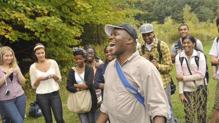 Professor Thembela Kepe with a group of students in a field setting with trees and grass