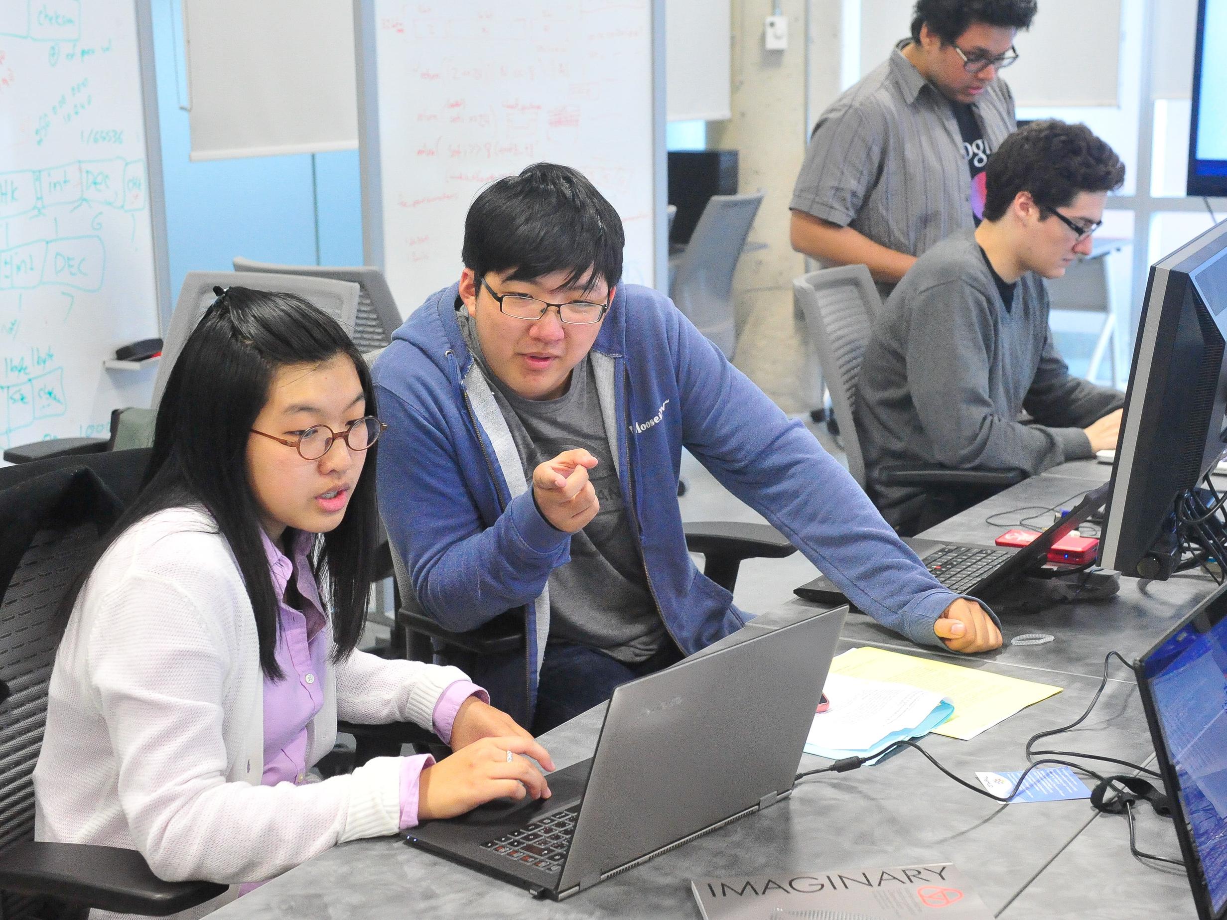 Two students collaborating at a laptop.