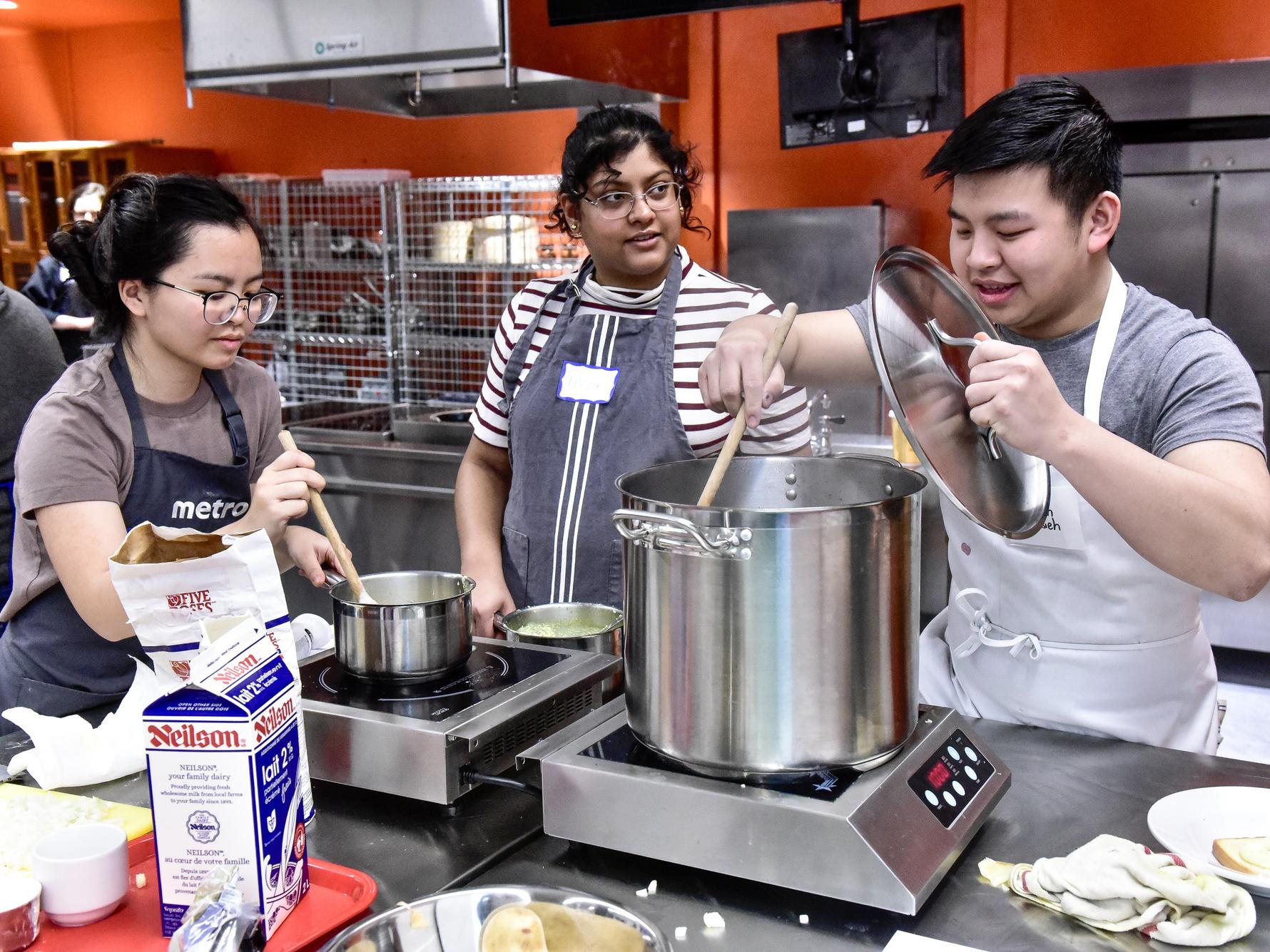 Three students cooking in the Culinaria lab 