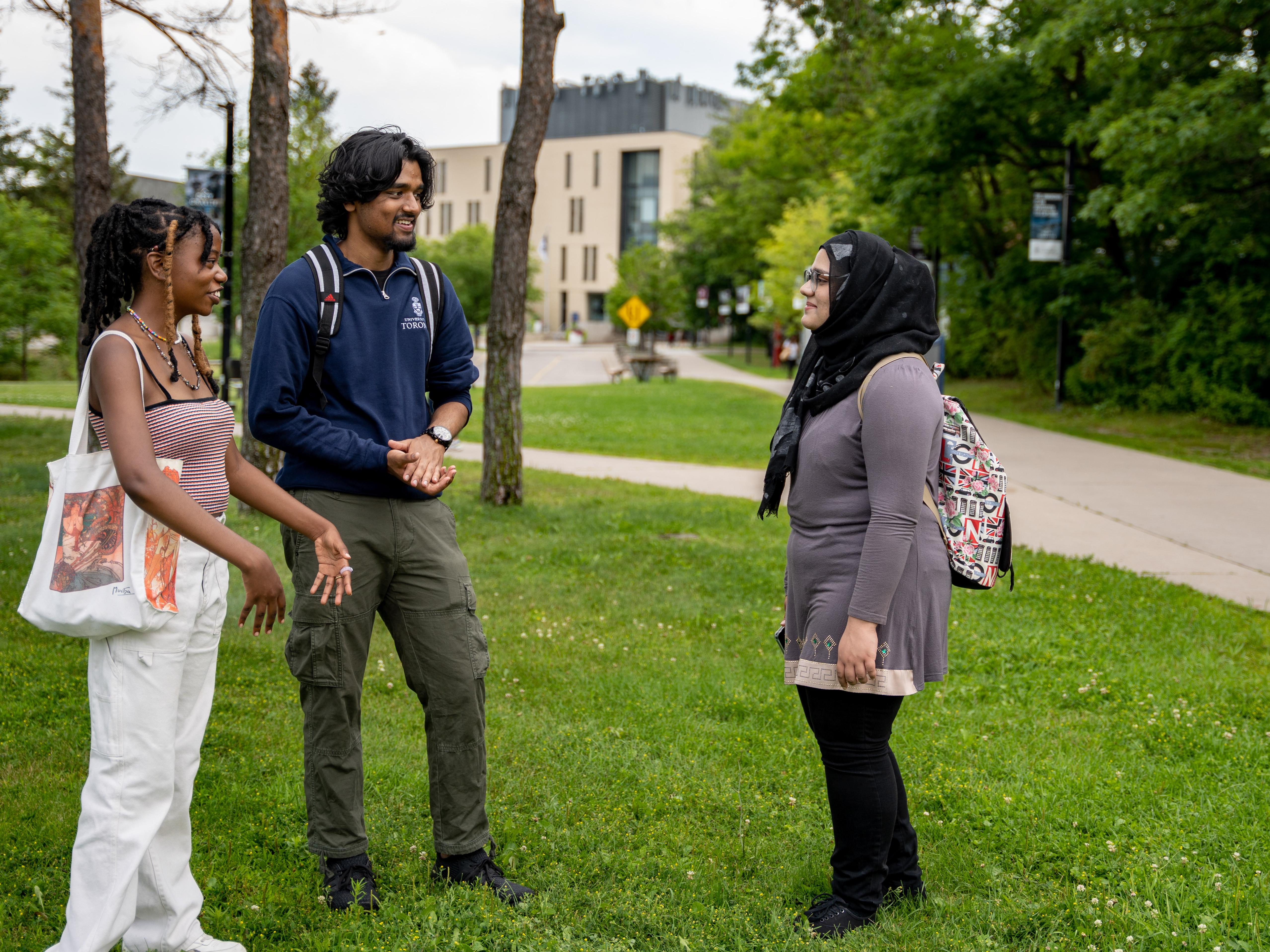 Students standing outside in discussion, with a building in the background