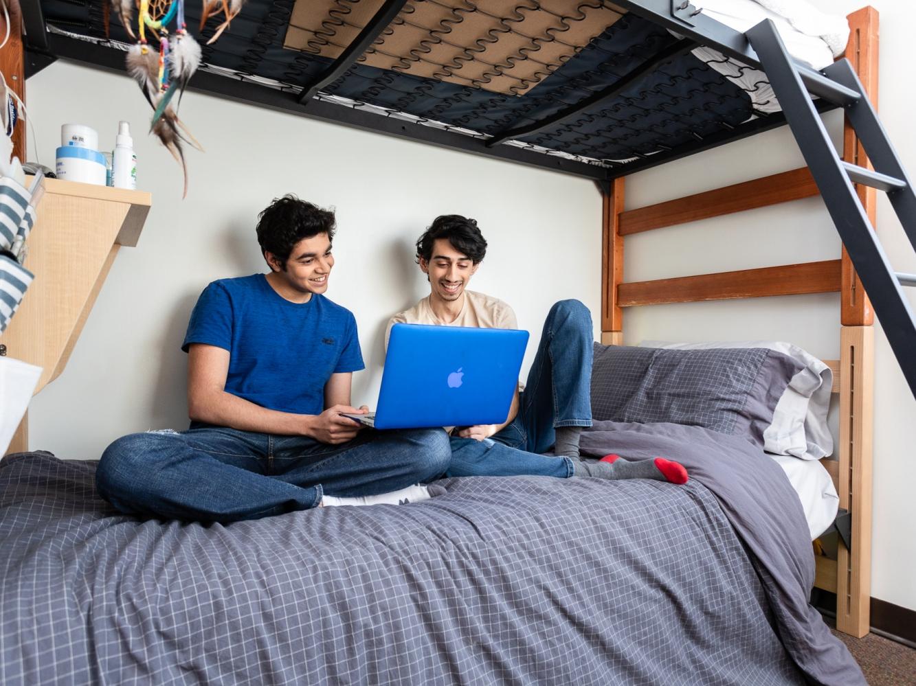 students sitting on a bed with a laptop