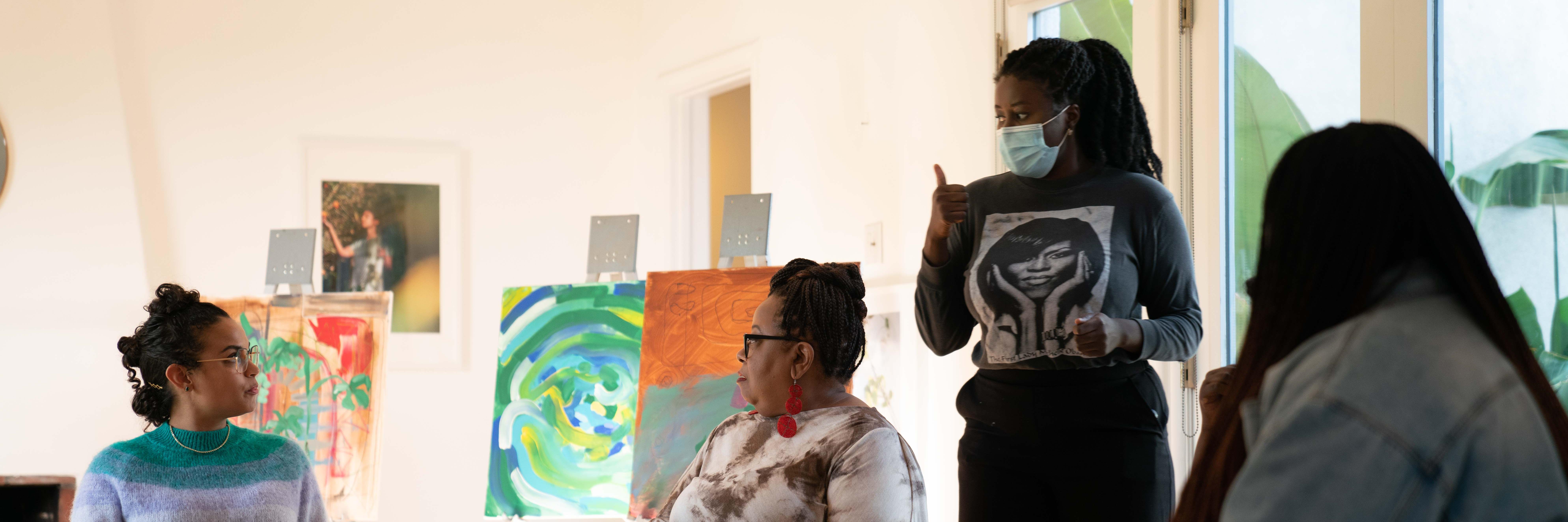 Nana on the set of her film Healing in Colour with three women in the film surrounded by paint canvasses