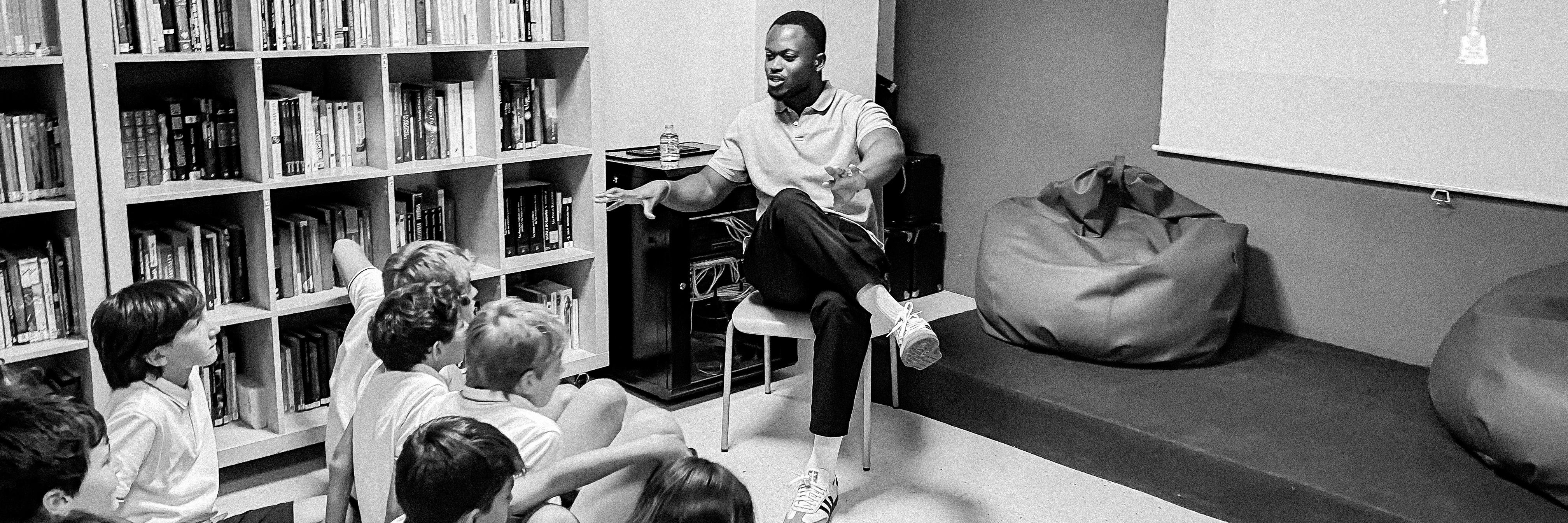 Black and white photo of Michael addressing a group of children in a library