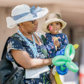 an alum holding her daughter with facepaints and a balloon animal