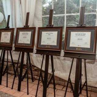 The four alumni awards in UofT frames propped up on easles
