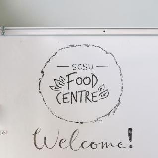 Illustrated logo of the Food Centre on a white board, with the word welcome under it