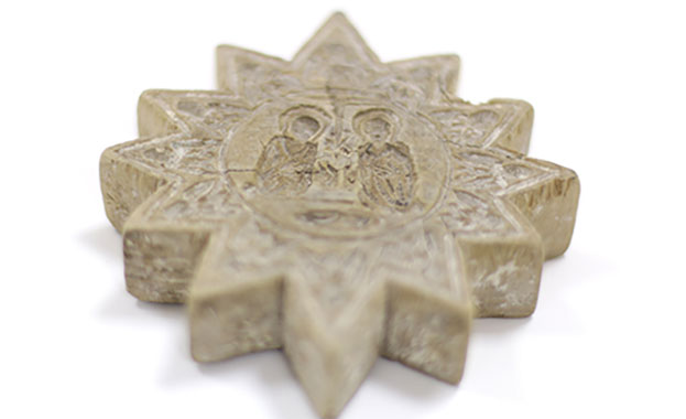 Star shaped stamp with 12 rays (or sun). It has a circle in the middle with an engraving of the image of Mary, Joseph and Jesus Christ.