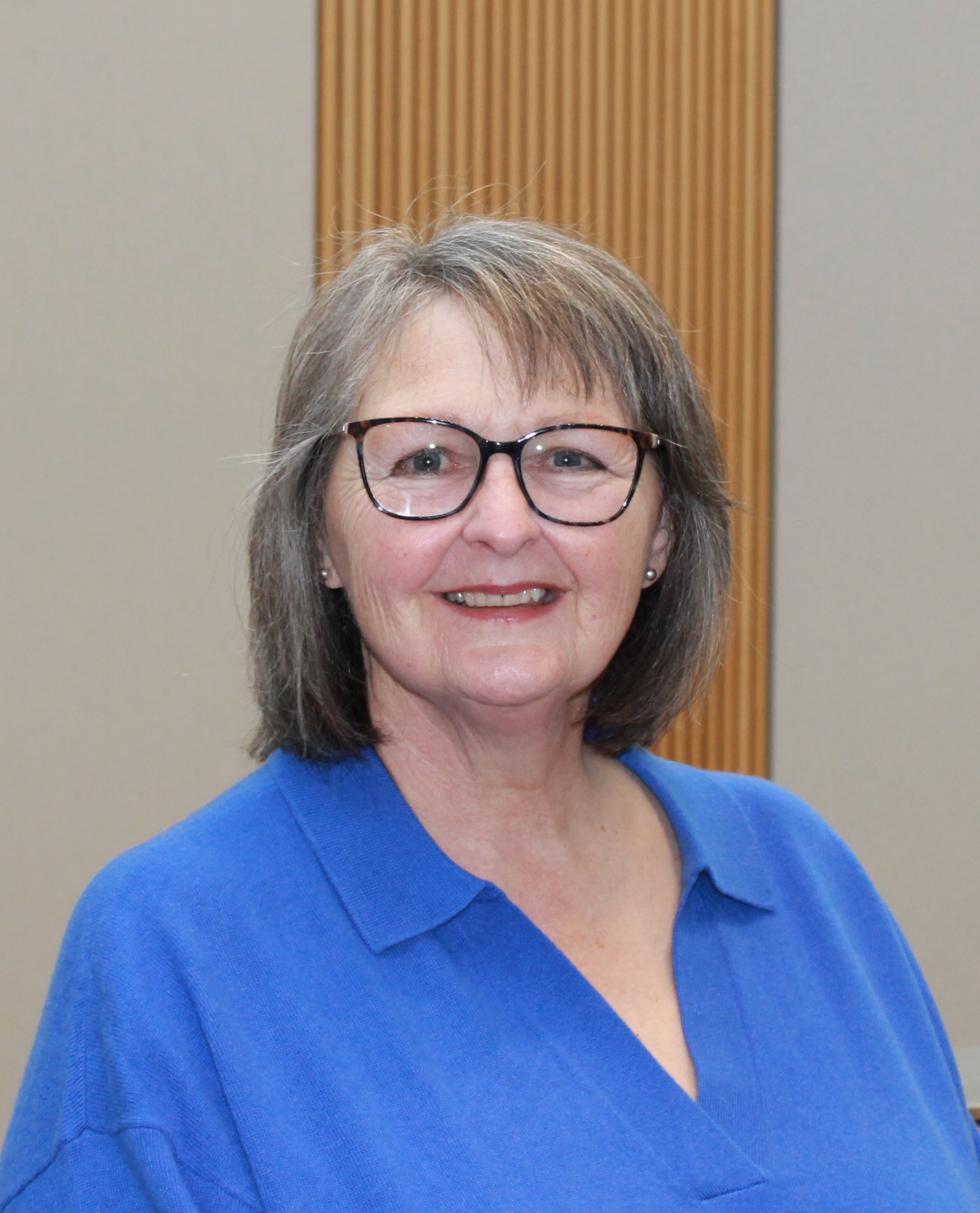 Donna Young, a white woman with grey hair and glasses, wearing a blue shirt.