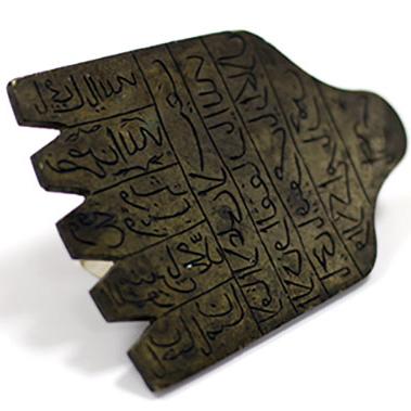 Close up of an amulet, a palm shaped stamp with prayer in Arabic inscribed on the surface