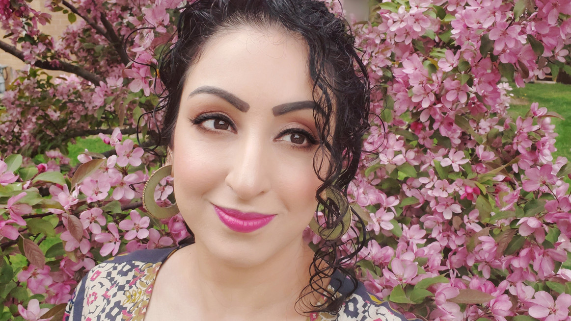 A photo of Sheniz in front of cherry blossoms in bloom