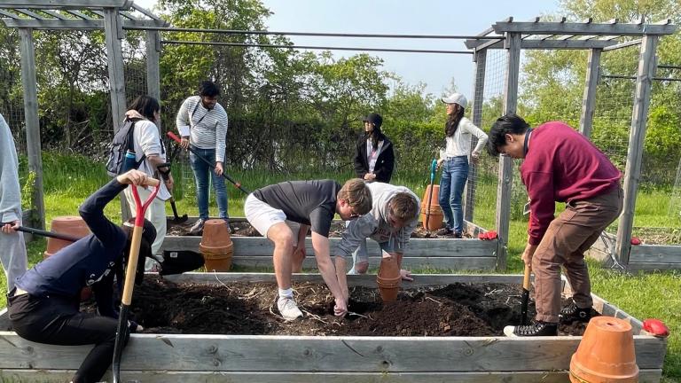 Students digging holes in planters for irrigation pots at Campus Farm