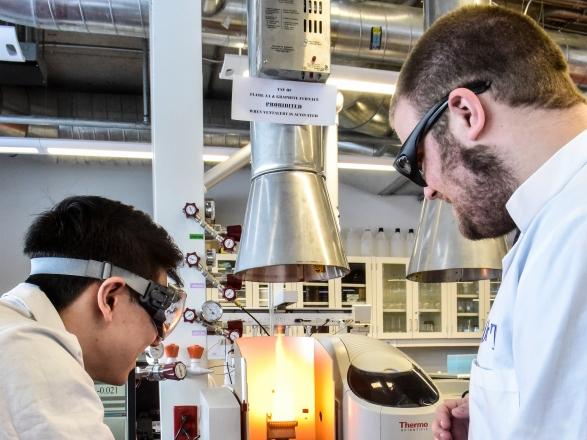 Two students performing an experiment using a Bunsen burner