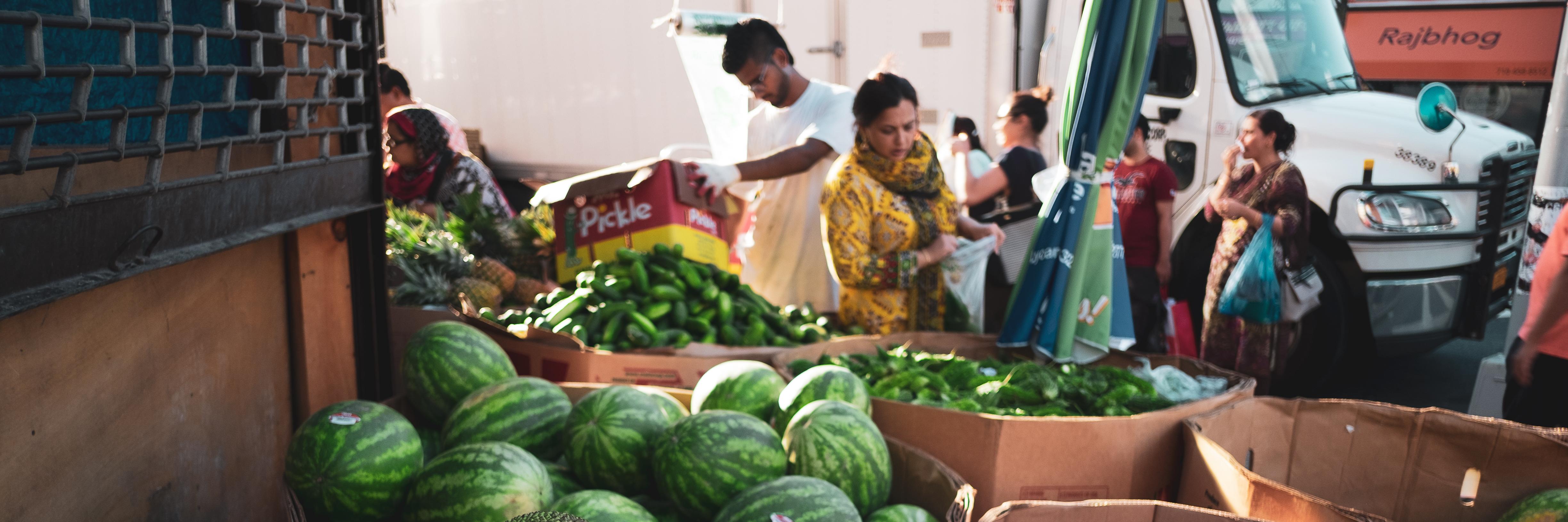people picking through vegetables in an urban market 