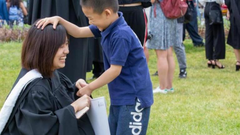 child patting a woman graduate's head