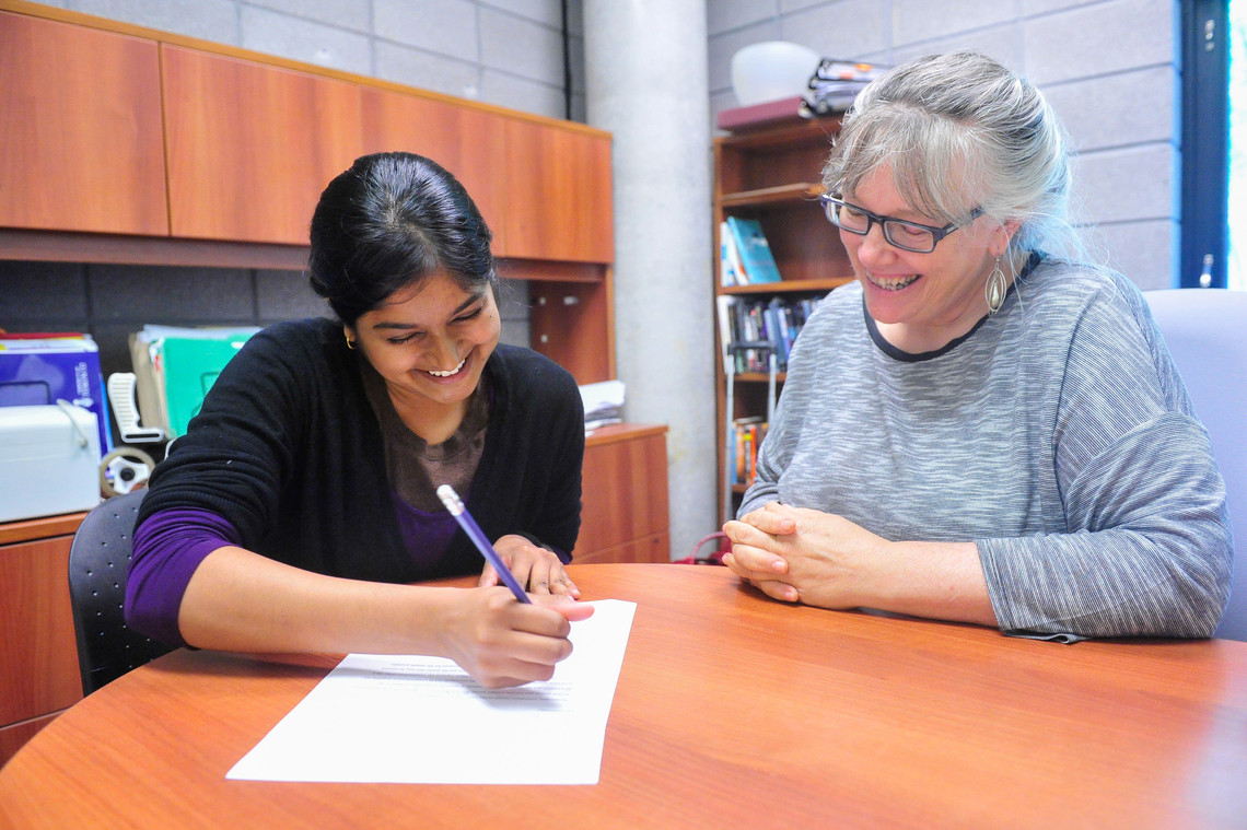 A student works with a writing instructor in an office