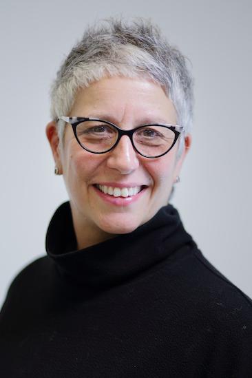 Jessica Fields, a woman with short gray hair and glasses wearing a black turtleneck