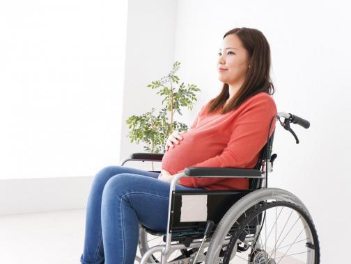 A pregnant woman sitting in a wheelchair