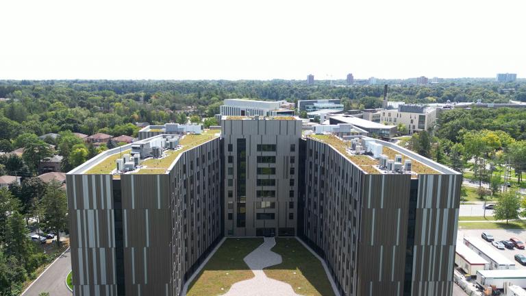 A drone shot of Harmony Commons, with green rooftops in a u shape and the neighbourhood horizon behind