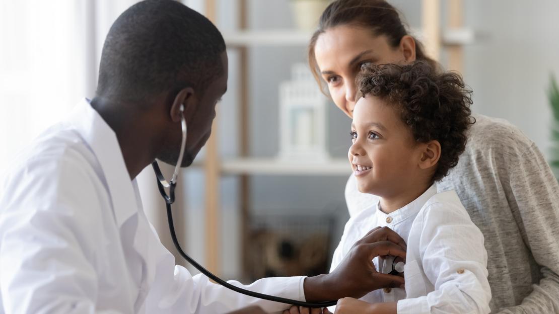 A doctor examining a child at an appointment with a stethoscope.