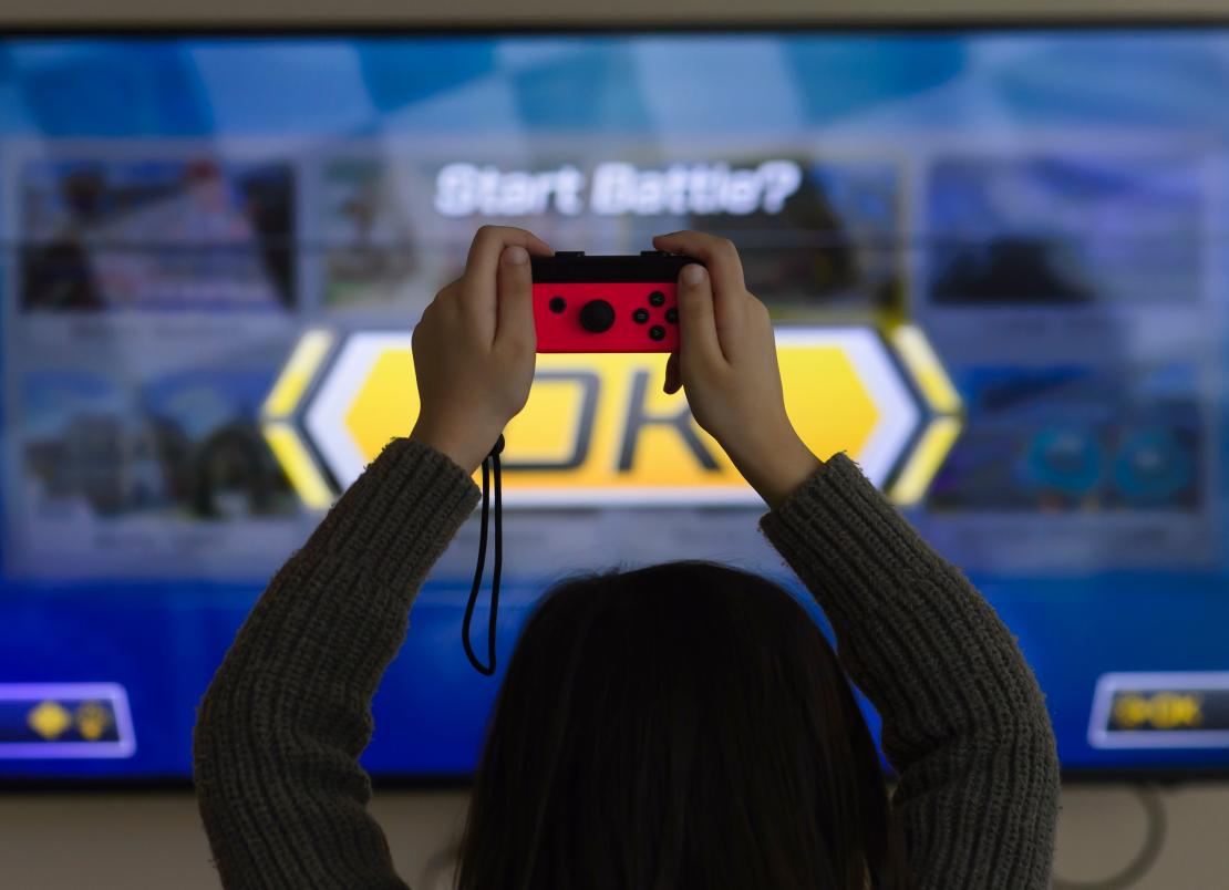 A woman playing Mario Kart with a Nintendo Switch controller