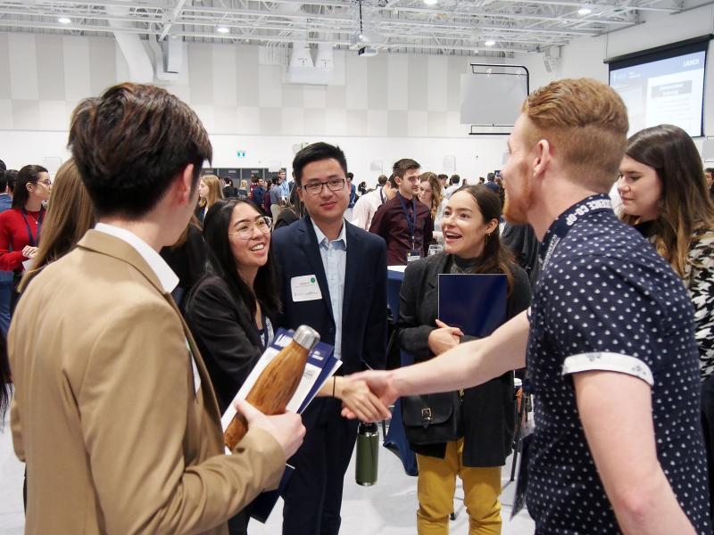 Students shaking hands with an employer at networking event.jpg