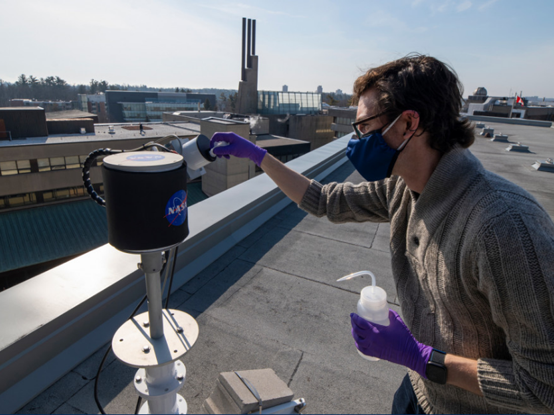 Assistant Professor Dan Weaver with an atmospheric device on top of a roof