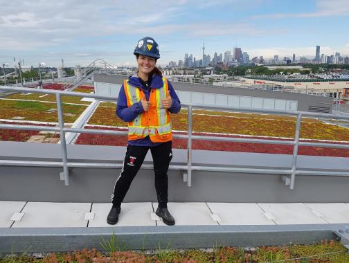 Student intern on top of building with Toronto skyline in background