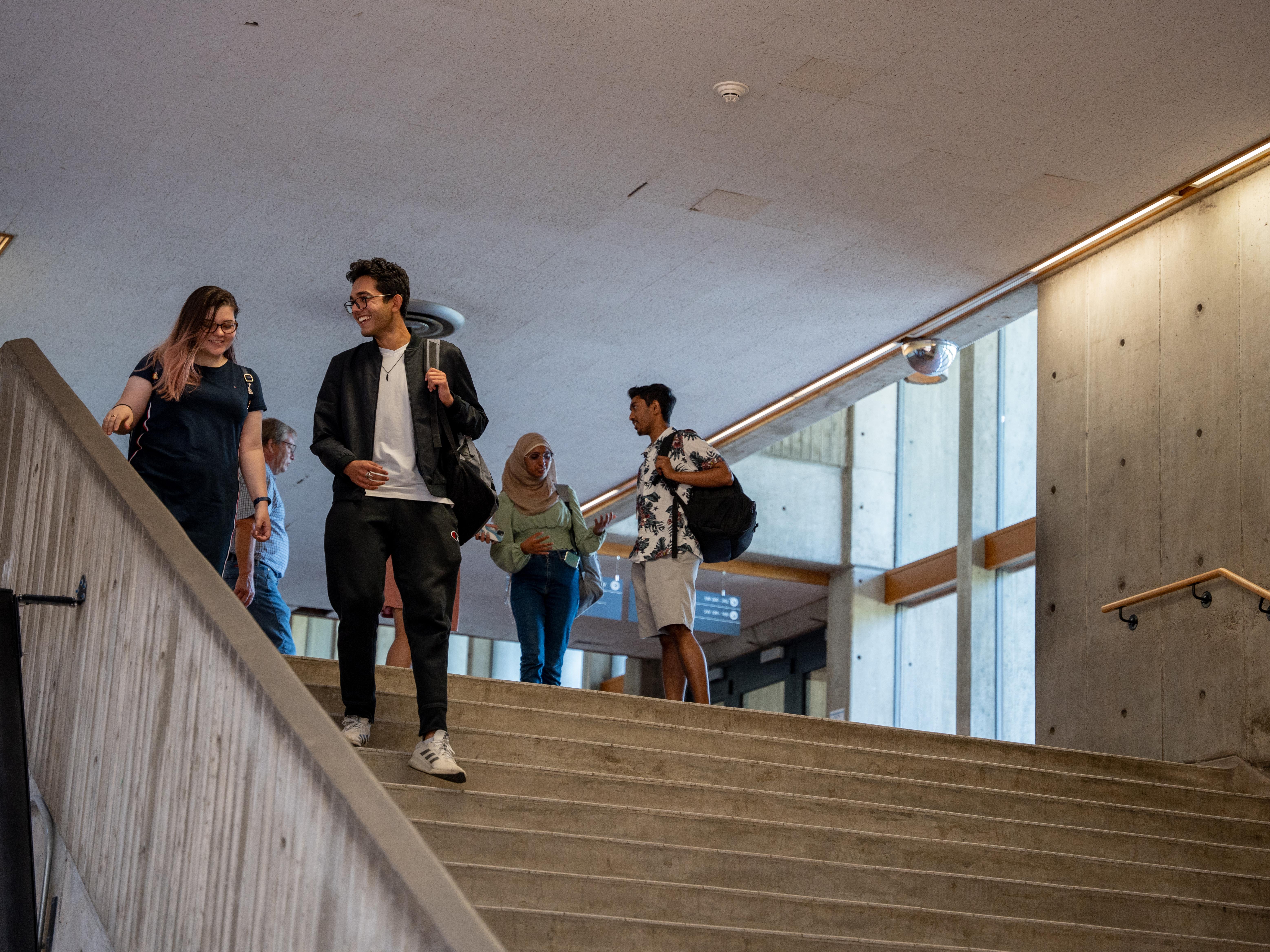 Two students walking down staircase in the Meeting Place