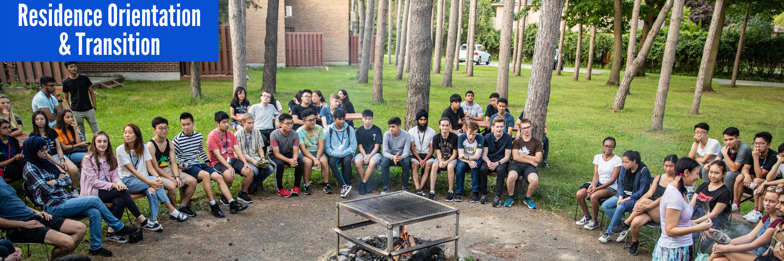 Photograph of residence students sitting around the bonfire pit behind Hickory & Grey Pine halls participating in an Indigenous Learning Circle during Residence Orientation.