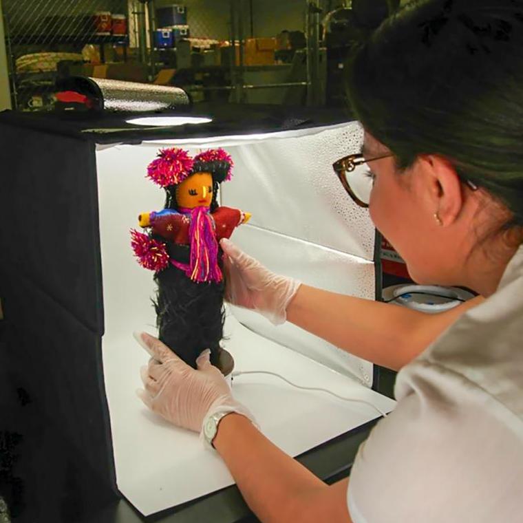 Historian María de Lourdes Orozco Cuautle positions a doll in a display box