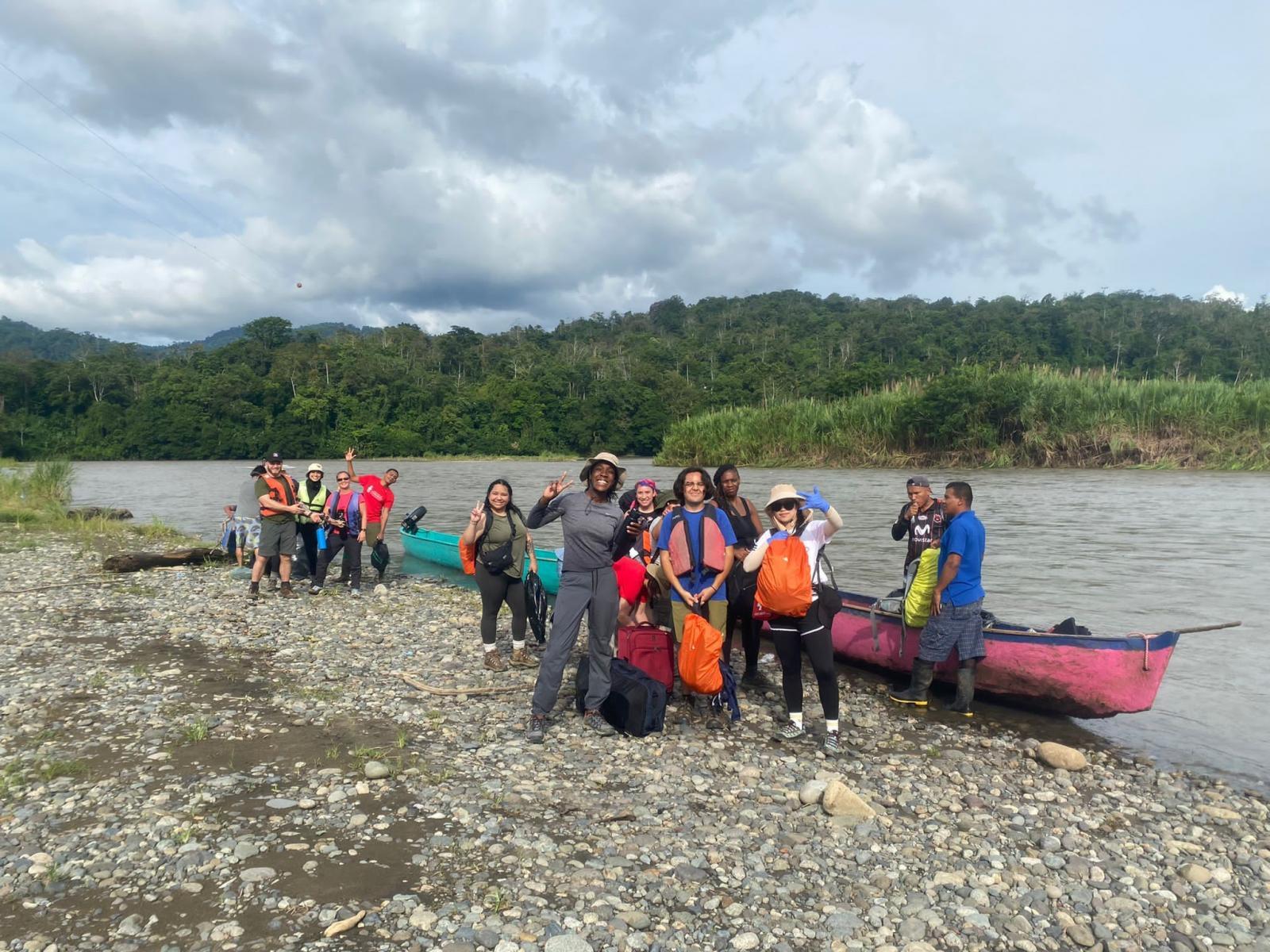 Students beside kayak on river through jungle