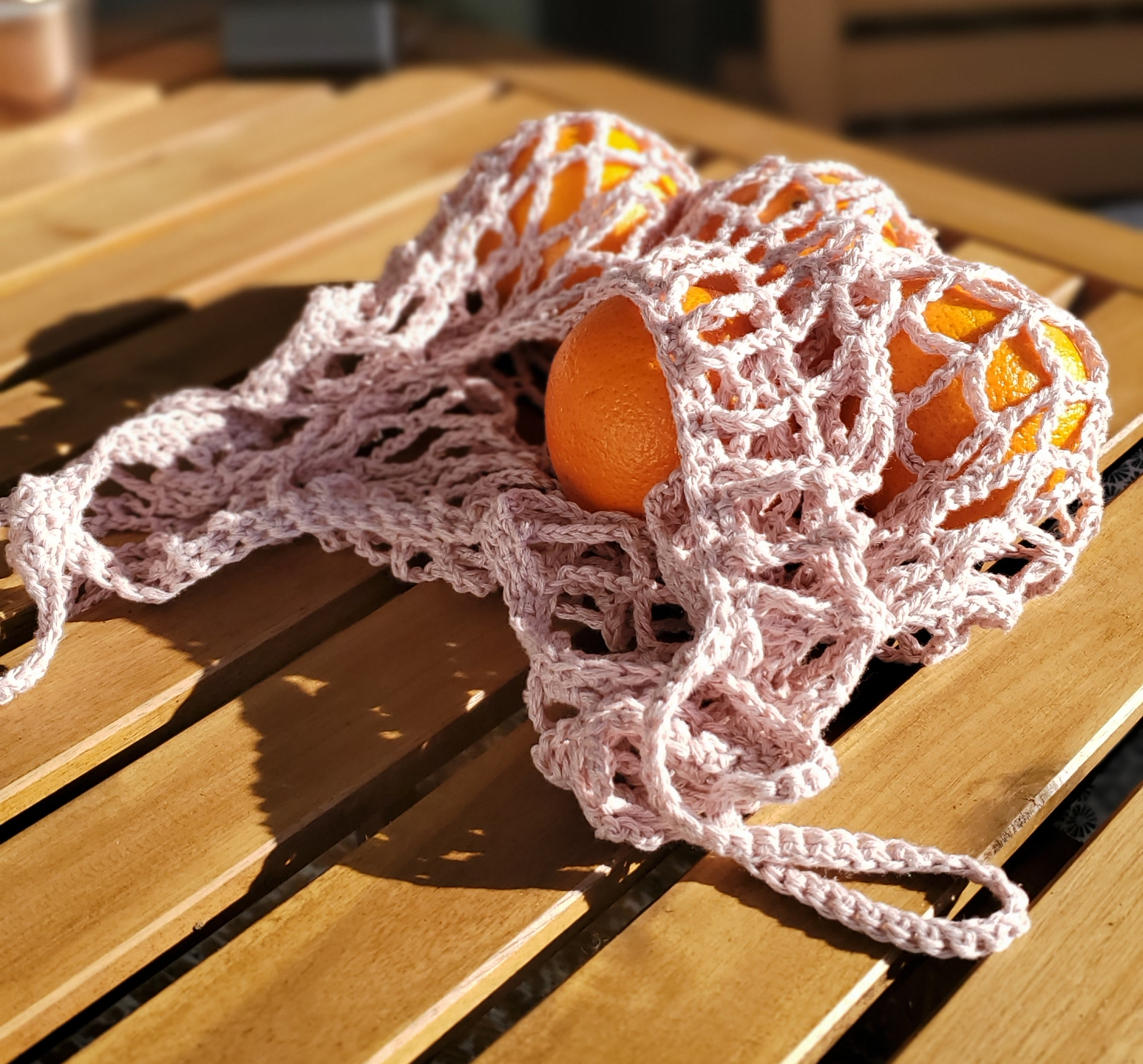 A white crocheted grocery bag with an orange inside