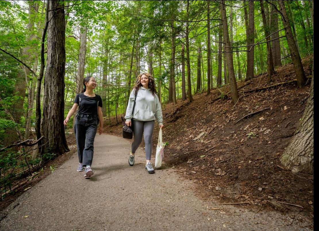 Two students walk in the UTSC grounds forest