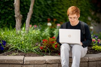 Student studying next to a campus garden bed