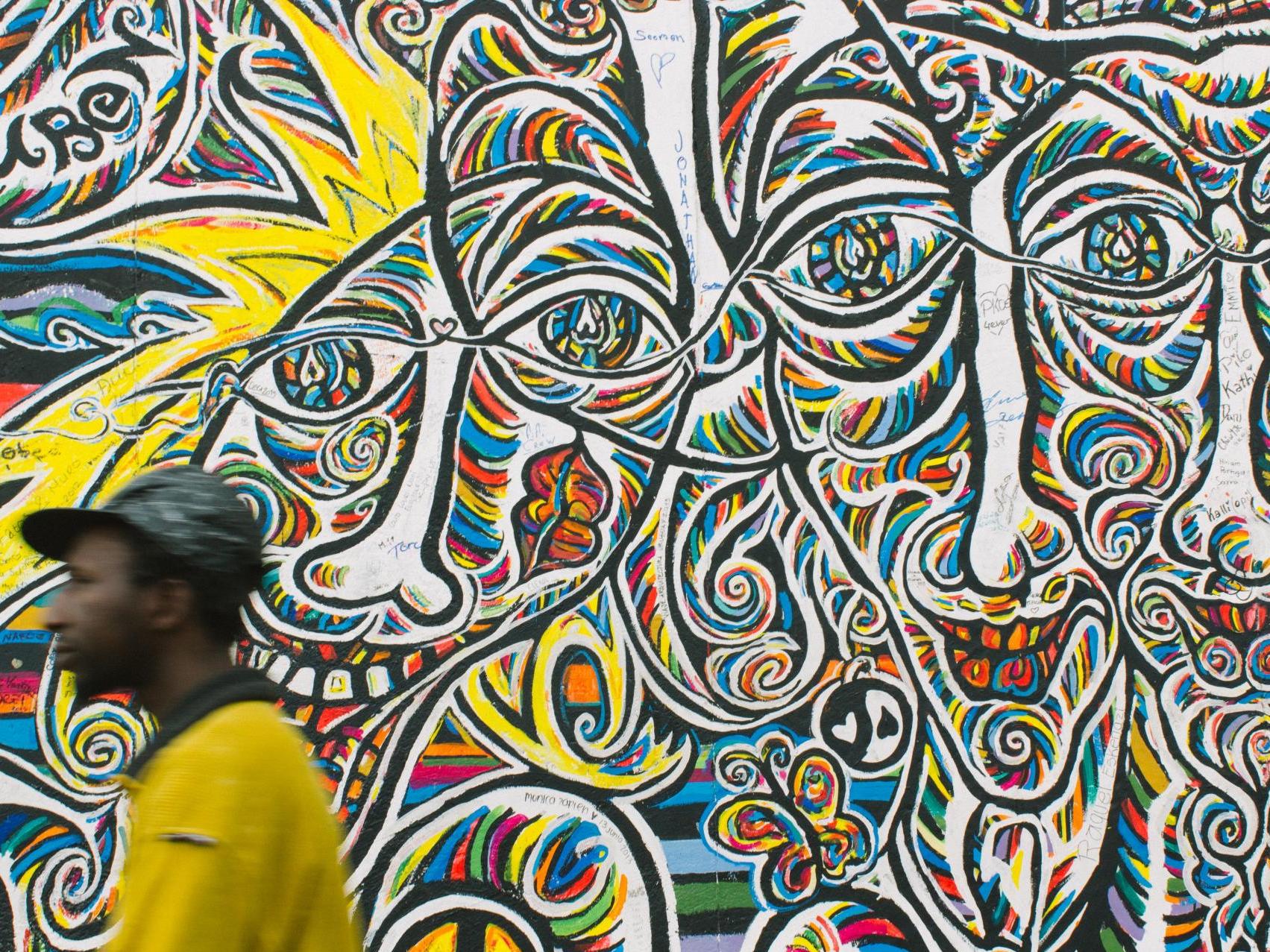 Man walking in front of a mural
