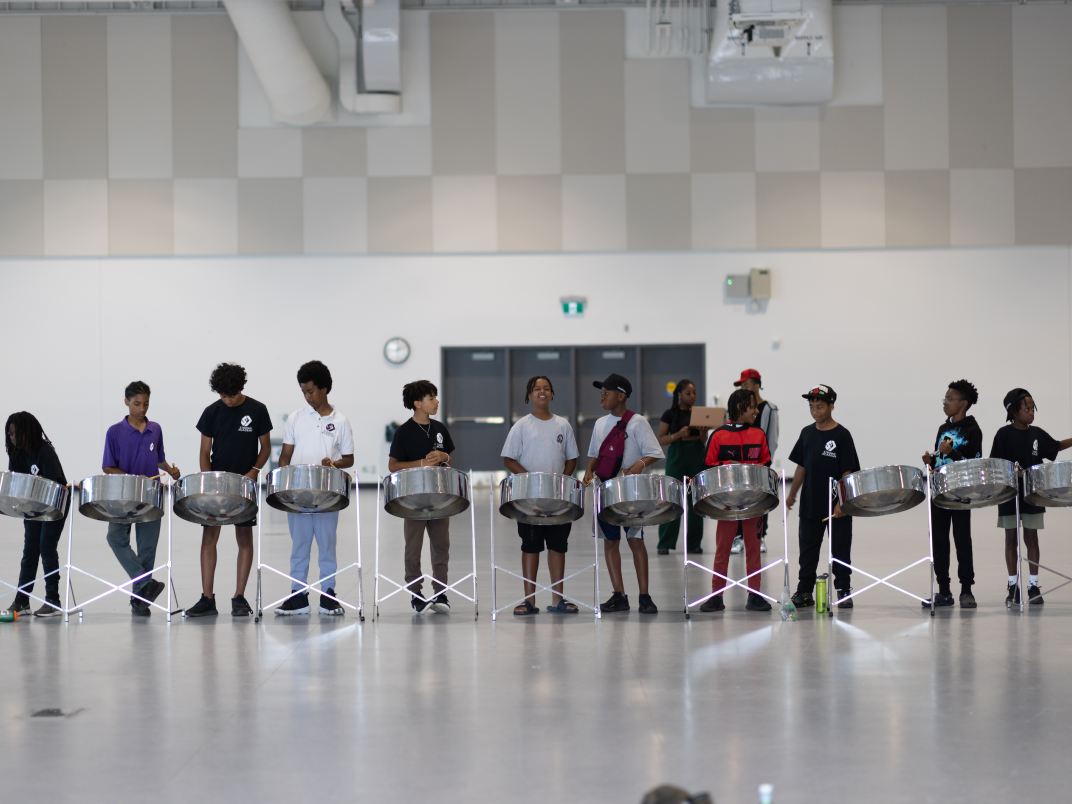 100 Strong participants lined up playing steel drums in the gym