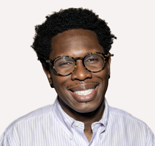 Tosen Nwadei smiling wearing glasses and a striped shirt