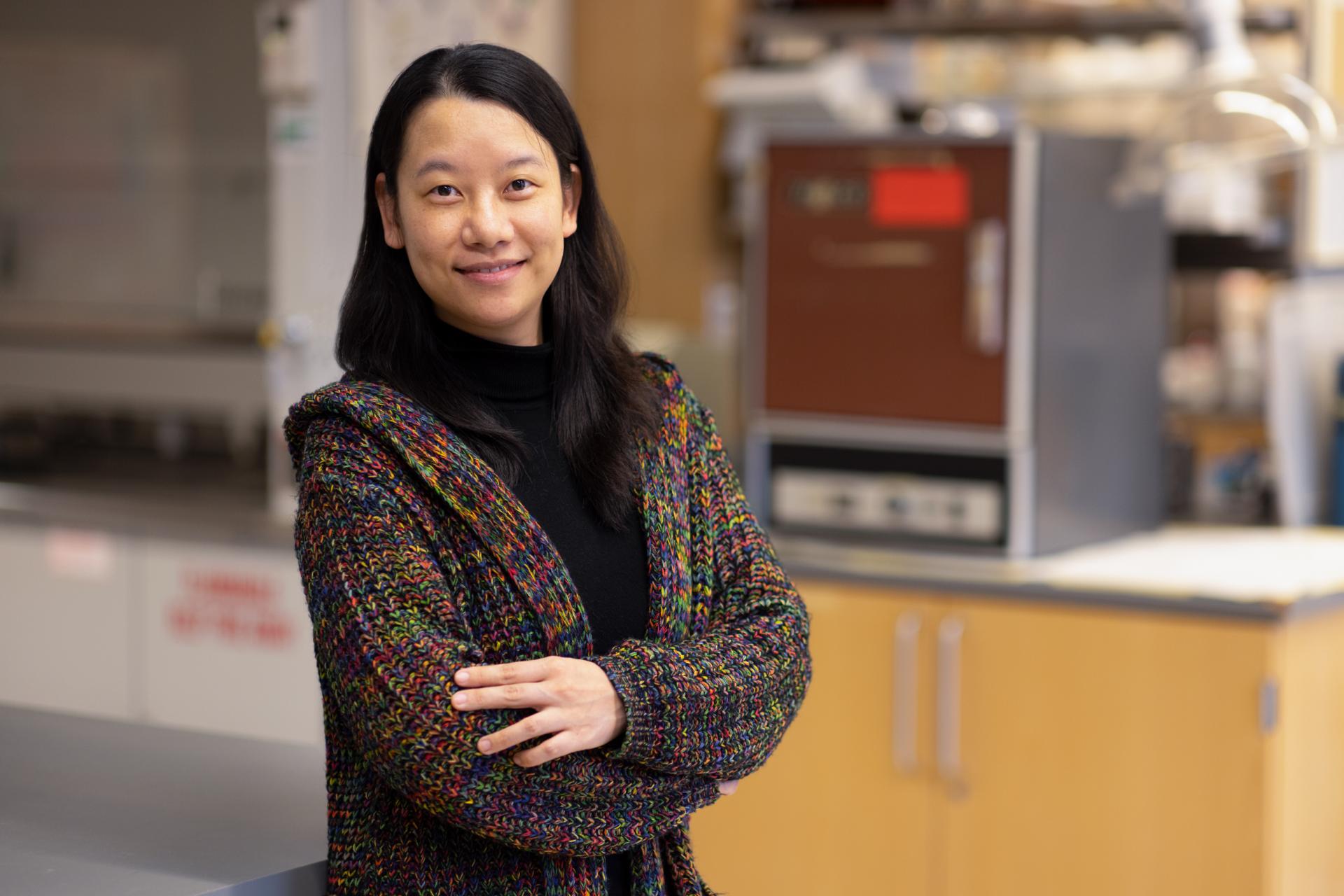 Professor Xue Pan in a sweater standing in a lab