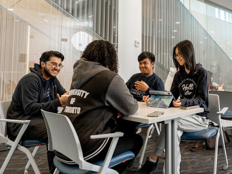 Students working together at a table in a glass enclosed meeting room in Highland Hall