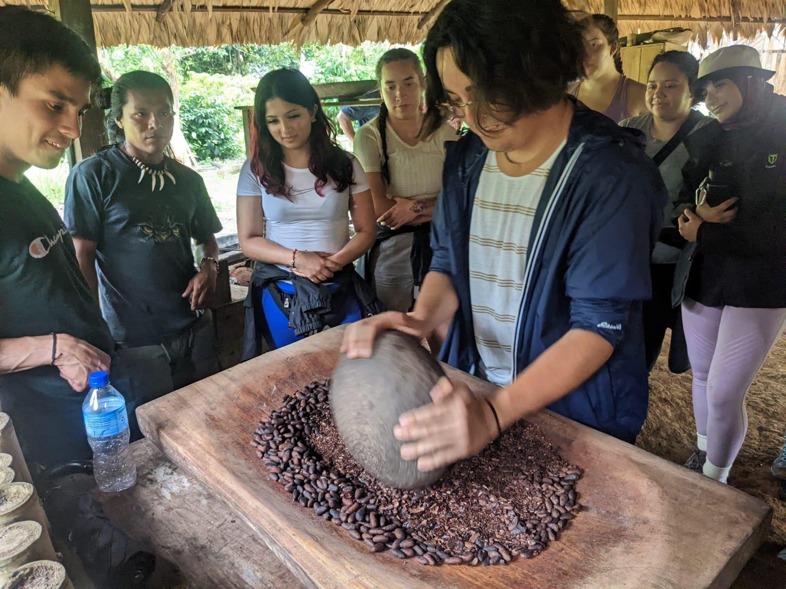 Global Field Trip students crushing beans in Costa Rica with community members explaining process