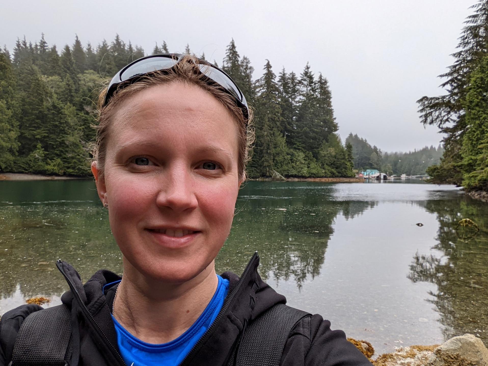 Professor Cosima Porteous in front of a lake view with reflected trees in water