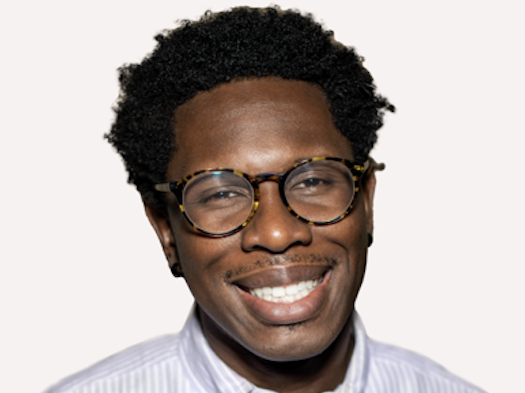 Tosen Nwadei smiling wearing glasses and a striped shirt